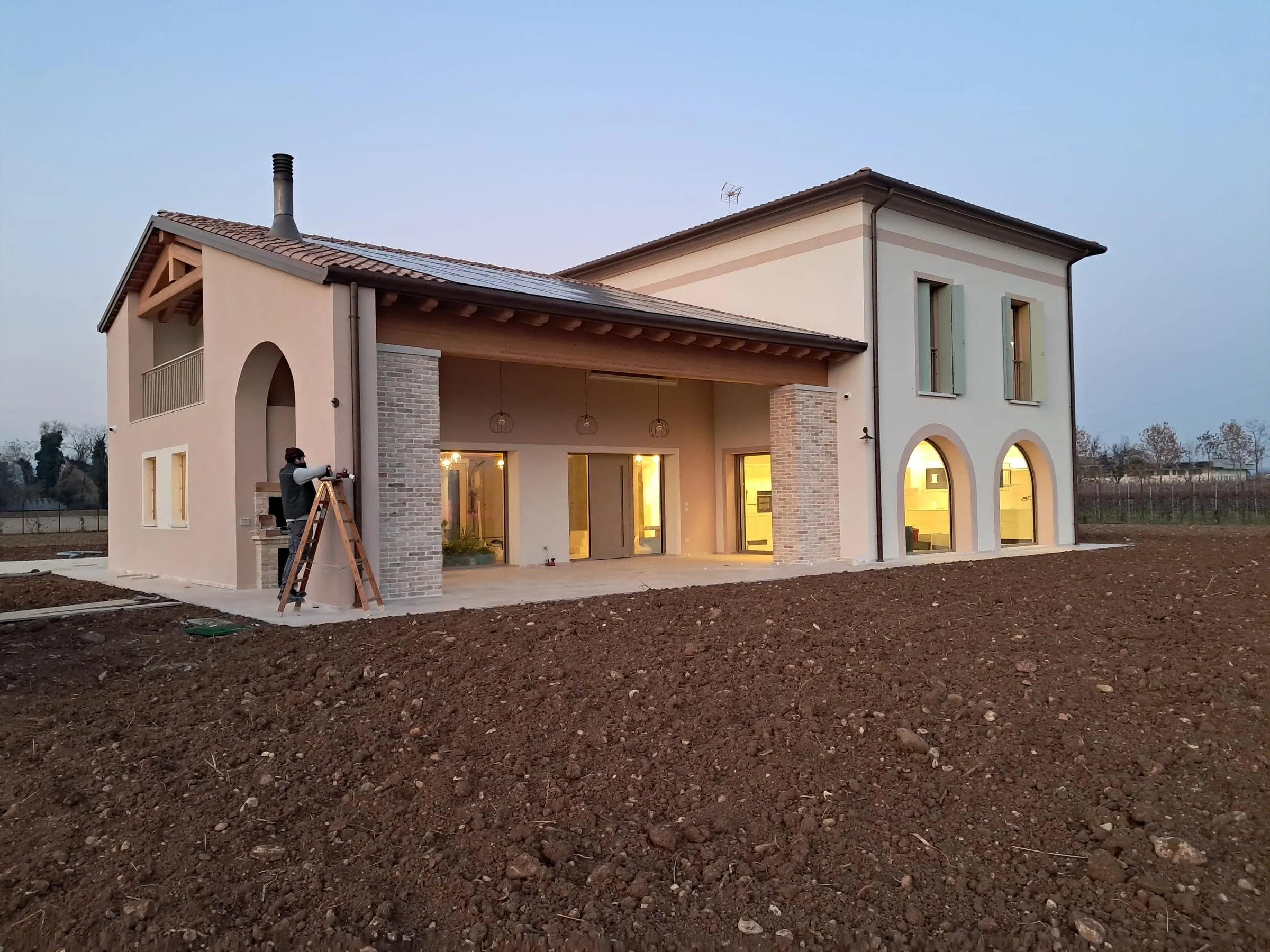 Casa C, vista esterna al crepuscolo con il portico ad archi illuminato